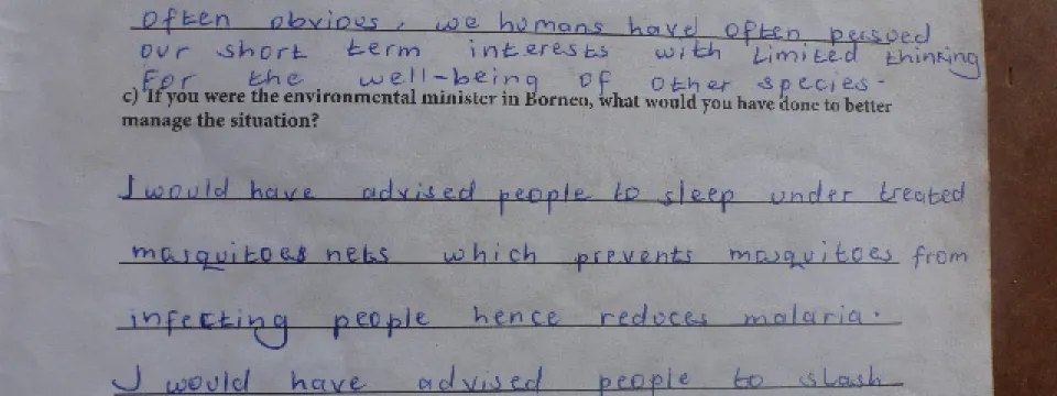 A handwritten response to a question about biodiversity that states: "Biodiversity shapes and supports every part of our existence. But these connections are not often obvious, we humans have pursued our short term interests with limited thinking for the well-being of other species." Below this, in response to a hypothetical question about being the environmental minister in Borneo, the text suggests advising people to sleep under mosquito nets and to slash vegetation around homes to reduce breeding areas.