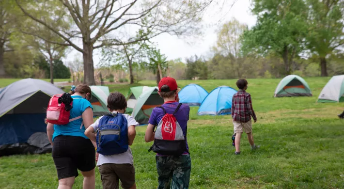 Kids hiking towards their pitched tents at a zoo camp.