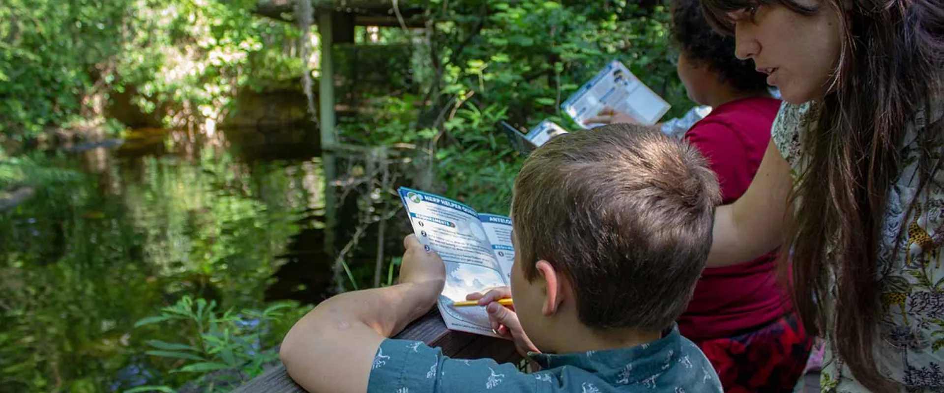 A mother helps her son with a Zoo Trekker activity at the alligator habitat.