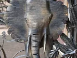 Close-up of a metal elephant design surrounded by other plants and filigree on the larger African Gates.