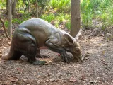A life-like bronze statue of an Aardvark, poised and digging in the dirt. It is a dog sized animal with a long, thick tail and longer, cylindrical snout and ears.