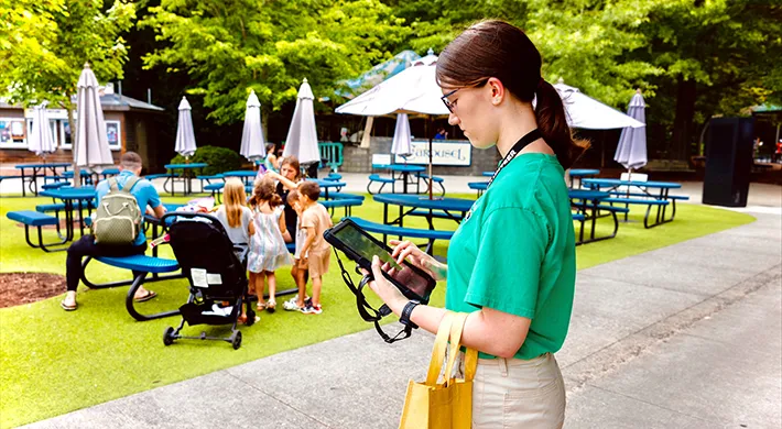 An intern at the Zoo reviewing a guest survey on a tablet.
