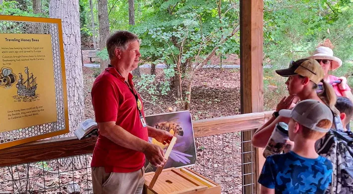 Volunteer talking with a group of guest at the Honey Bee habitat