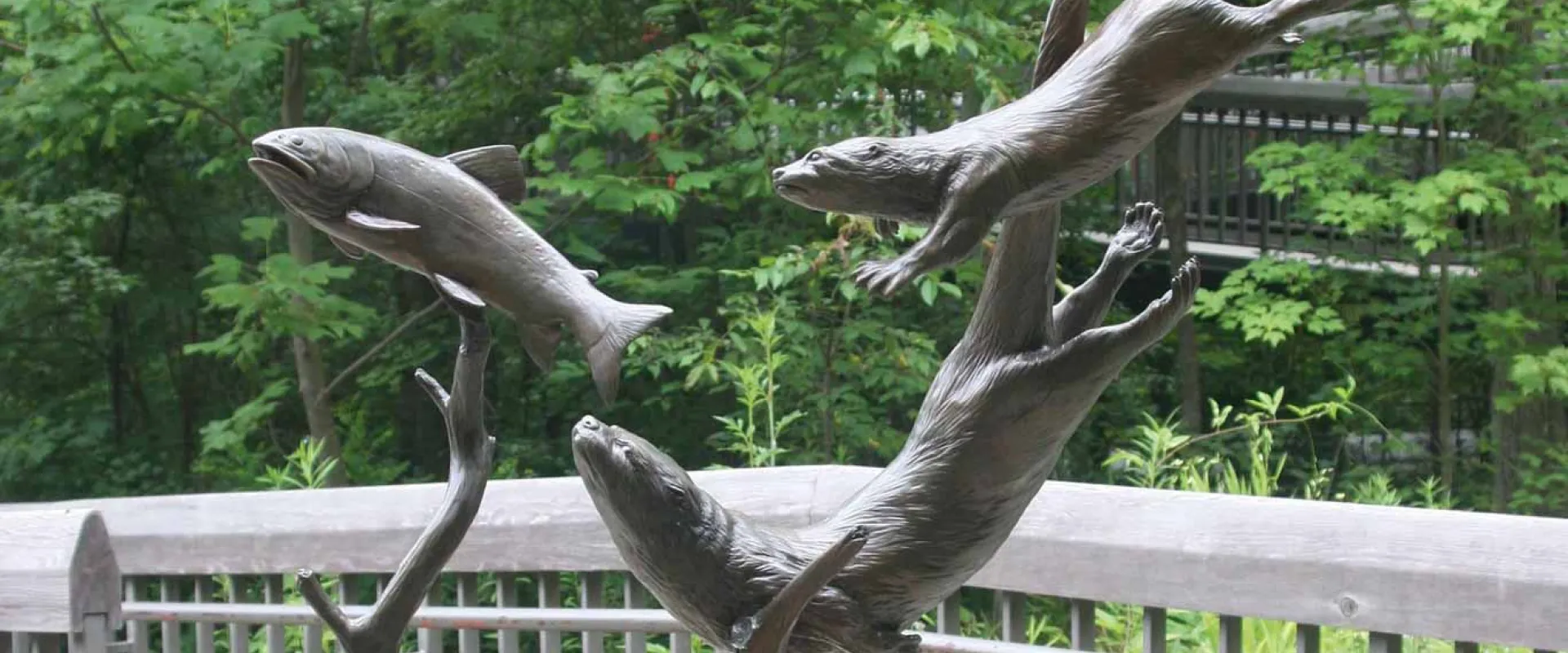 A bronze statue of several otters poised mid-frolic as they would be in the water.