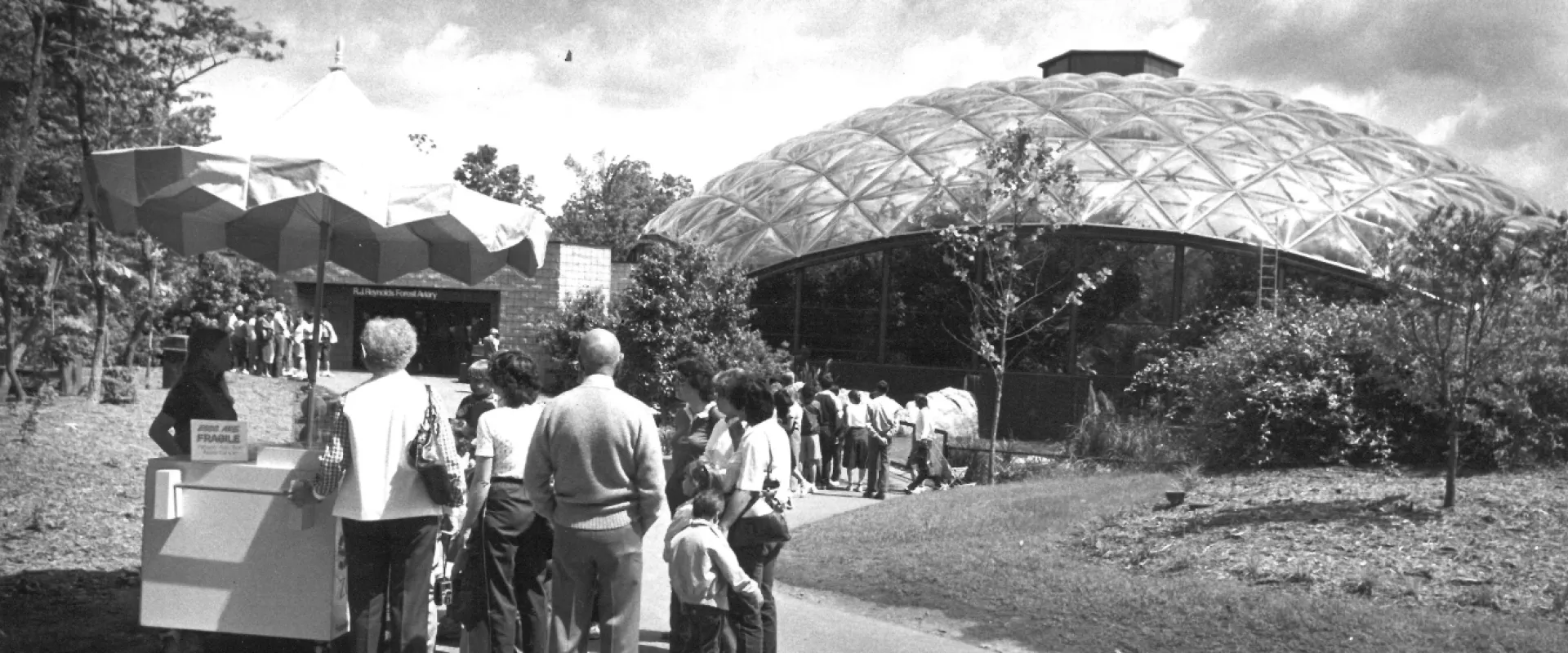 A black and white photo of guests entering the Zoo's aviary building. 