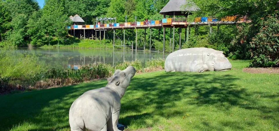 Two limestone hippos with the Africa bridge in the backgorund.