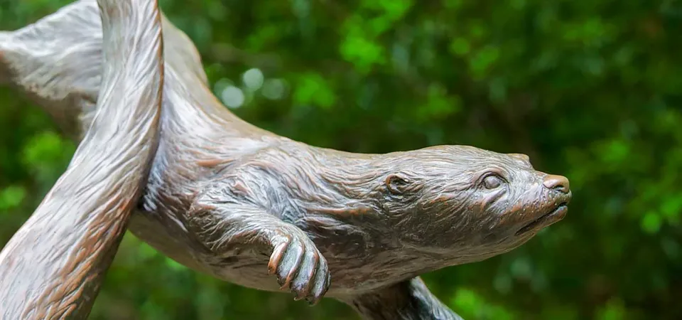 A bronze statue of several otters poised mid-frolic as they would be in the water.