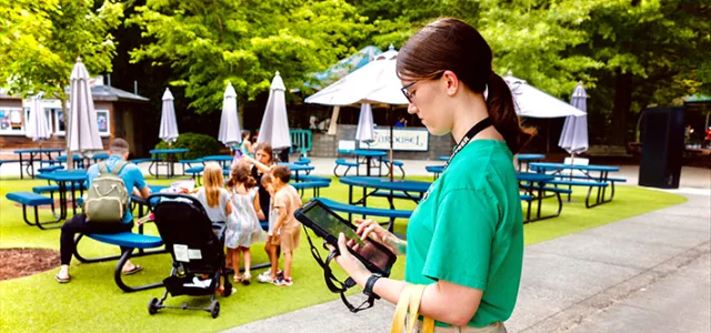 An intern at the Zoo reviewing a guest survey on a tablet.
