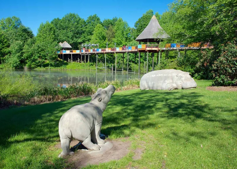 Two limestone hippos with the Africa bridge in the backgorund.